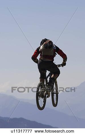 Stock Photo - Mountain biker jumping into the air. Fotosearch