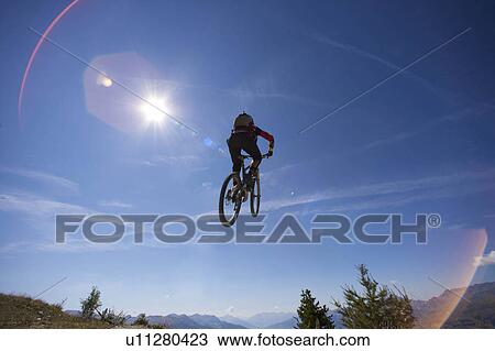 Stock Image - Mountain biker jumping over head. Fotosearch