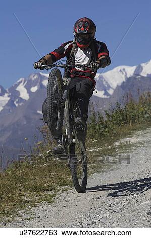 Stock Image - Mountain biker pulling a wheelie. Fotosearch