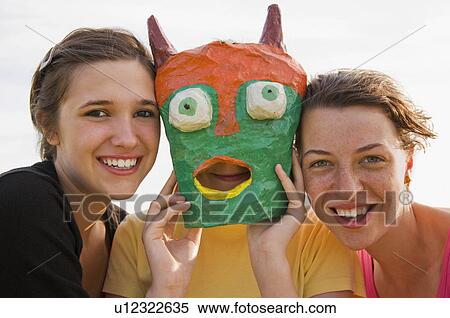 Three girls, one wearing a mask View Large Photo Image Stock Photography - Three girls, one wearing a mask. Fotosearch
