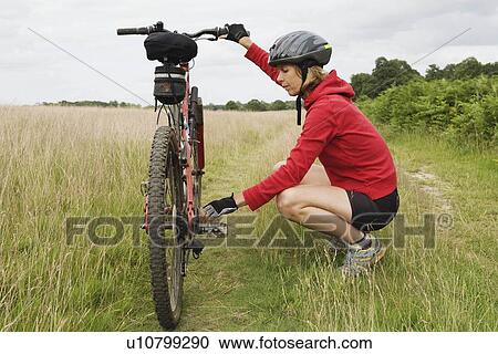 Woman cyclist fixing bicycle View Large Photo Image Stock Image - Woman cyclist fixing bicycle. Fotosearch