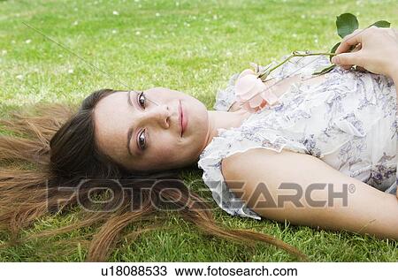 Woman laying on grass, holding rose View Large Photo Image Stock Image - Woman laying on grass, holding rose. Fotosearch