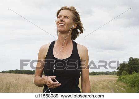 Woman runner listening to music on ipod View Large Photo Image Stock Photo - Woman runner listening to music on ipod. Fotosearch