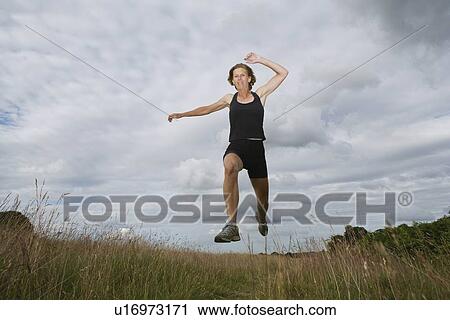 Stock Image - Woman running on dirt track. Fotosearch