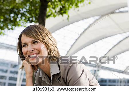 Stock Image - Woman sitting outdoors smiling. Fotosearch