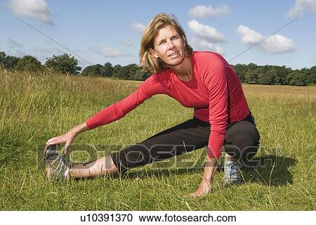Woman stretching leg in field View Large Photo Image Stock Image - Woman stretching leg in field. Fotosearch
