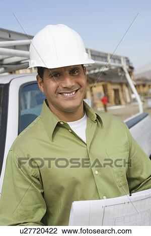 Architect holding blueprints on construction site View Large Photo Image Stock Image - Architect holding blueprints on construction site. Fotosearch