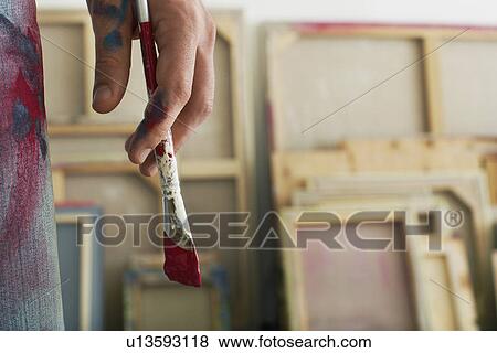 Artist holding paint brush standing in studio close up on hand View Large Photo Image Stock Photo - Artist holding paint brush standing in studio close up on hand. Fotosearch