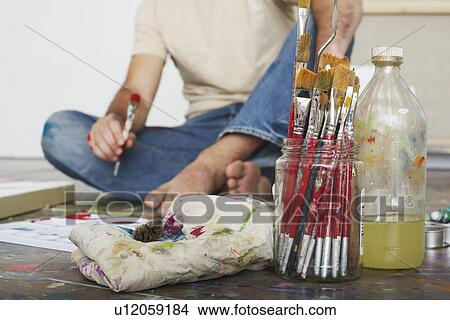 Picture - Artist sitting on floor focus on paint brushes and materials. Fotosearch