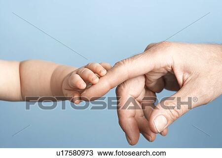 Stock Image - Baby and Man touching hands close-up on hands. Fotosearch