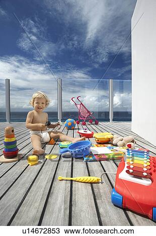 Stock Image - Baby Boy Playing on Porch with lots of toys. Fotosearch