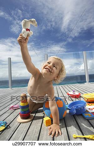 Stock Photo - Baby Boy Playing on Porch with lots of toys. Fotosearch