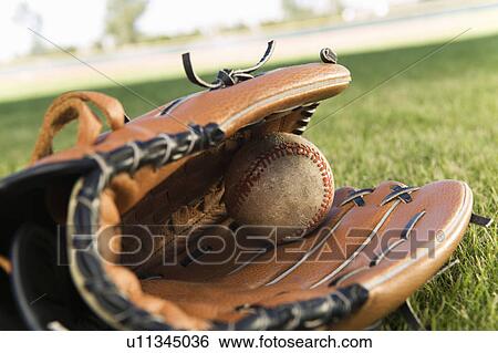 Baseball glove and ball on field (close-up) View Large Photo Image Stock Photograph - Baseball glove and ball on field (close-up). Fotosearch