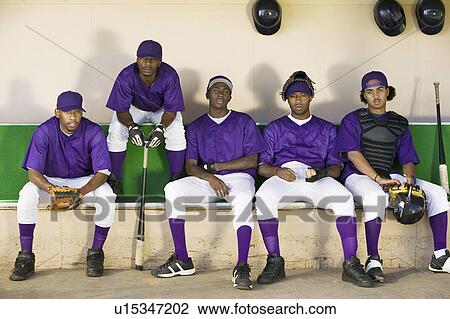 Stock Image - Baseball team sitting in dugout (portrait). Fotosearch
