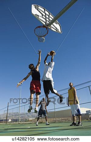 Basketball player mid-air shooting ball into hoop while another guards him low angle view View Large Photo Image Stock Photography - Basketball player mid-air shooting ball into hoop while another guards him low angle view. Fotosearch