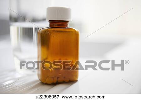 Bottle of pills next to water on table close up View Large Photo Image Stock Photo - Bottle of pills next to water on table close up. Fotosearch