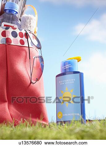 Bottle of suntan lotion and bag with beach items in grass close-up View Large Photo Image Stock Image - Bottle of suntan lotion and bag with beach items in grass close-up. Fotosearch