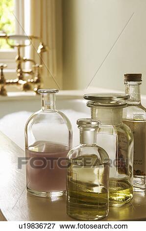 Stock Photo - Bottles of Bath Oils on edge of bathtub filled with bubbles. Fotosearch
