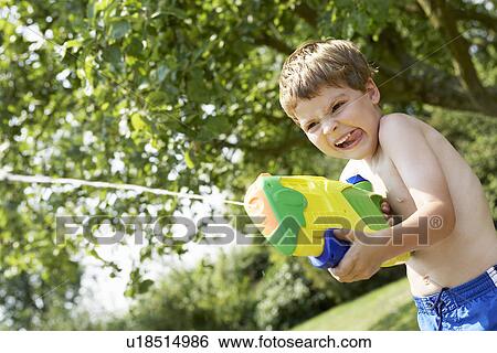 Boy in park shooting pump action water pistol View Large Photo Image Stock Photograph - Boy in park shooting pump action water pistol. Fotosearch