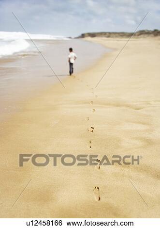 Boy walking along sandy beach back view View Large Photo Image Stock Photograph - Boy walking along sandy beach back view. Fotosearch