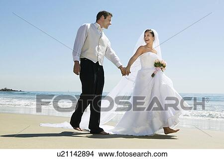 Bride and Groom walking on beach View Large Photo Image Picture - Bride and Groom walking on beach. Fotosearch