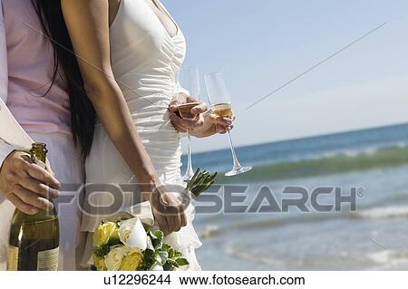 Bride and Groom with champagne at ocean (close-up) View Large Photo Image Picture - Bride and Groom with champagne at ocean (close-up). Fotosearch