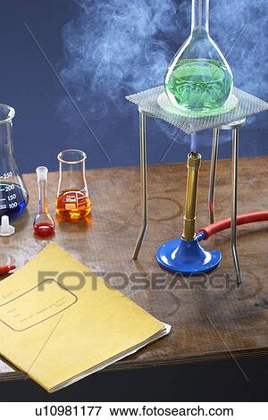 Stock Photo - Bunsen burner heating flask with science equipment in laboratory. Fotosearch