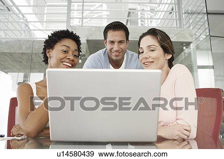 Stock Photo - Business colleagues using laptop in office. Fotosearch