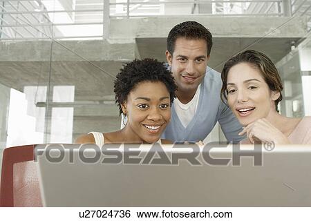 Stock Photograph - Business colleagues using laptop in office. Fotosearch