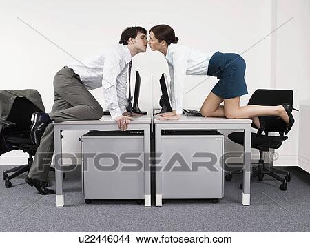 Business couple kissing over desks in office View Large Photo Image Picture - Business couple kissing over desks in office. Fotosearch