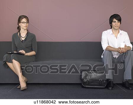 Stock Image - Business man and woman sitting on sofa. Fotosearch