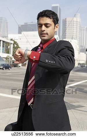 Stock Photograph - Business man checking watch on city street. Fotosearch