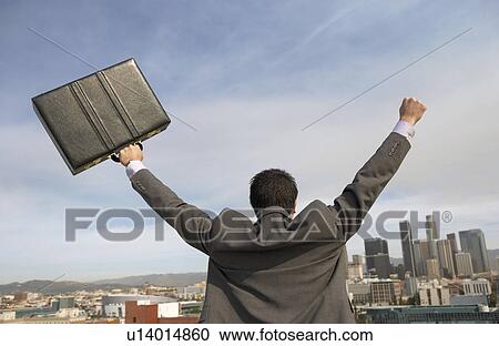 Stock Image - Business man cheering to city back view. Fotosearch