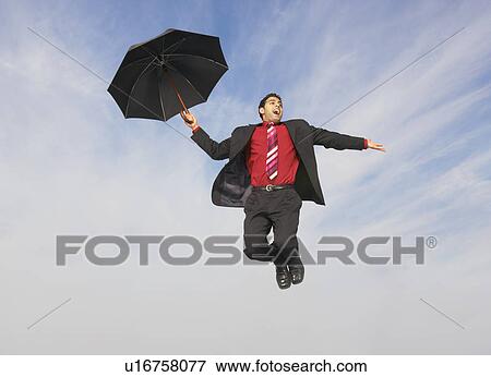 Business man flying with umbrella mid-air outdoors View Large Photo Image Stock Photo - Business man flying with umbrella mid-air outdoors. Fotosearch