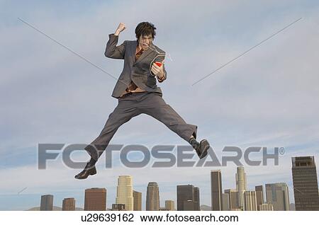Business man listening to mp3 player mid-air above city View Large Photo Image Stock Image - Business man listening to mp3 player mid-air above city. Fotosearch