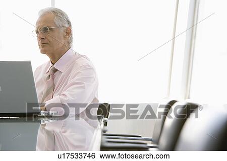 Business man using laptop in conference room View Large Photo Image Stock Photograph - Business man using laptop in conference room. Fotosearch