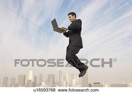 Business man using laptop mid-air above city View Large Photo Image Stock Photo - Business man using laptop mid-air above city. Fotosearch