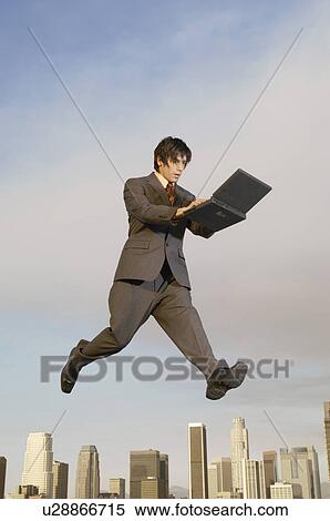 Business man using laptop mid-air above city View Large Photo Image Stock Photography - Business man using laptop mid-air above city. Fotosearch