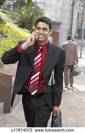 Stock Image - Business man using mobile phone on city street. Fotosearch