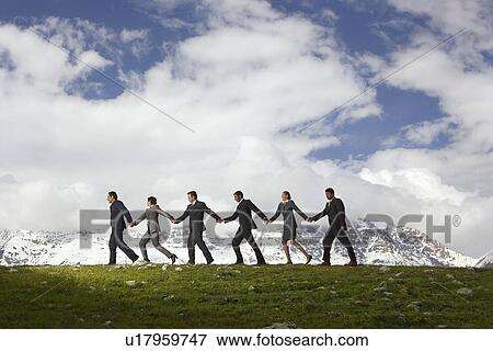 Business People Holding Hands and Walking through mountains side view View Large Photo Image Stock Photo - Business People Holding Hands and Walking through mountains side view. Fotosearch