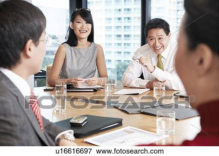 Stock Photo - Business people sitting round table in conference room. Fotosearch