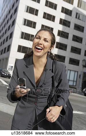 Picture - Business woman holding mobile phone on city street. Fotosearch