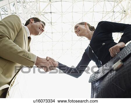 Picture - Businessman and businesswoman shaking hands (low angle view). Fotosearch