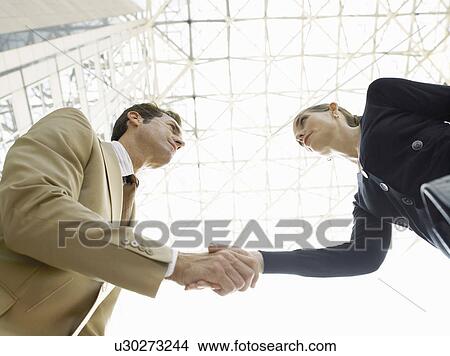 Picture - Businessman and businesswoman shaking hands (low angle view). Fotosearch