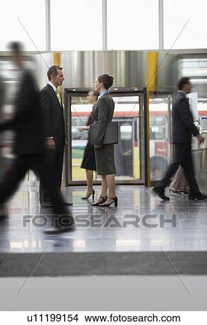 Businessman and businesswoman standing and talking in office building lobby View Large Photo Image Picture - Businessman and businesswoman standing and talking in office building lobby. Fotosearch