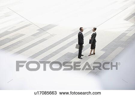 Businessman and businesswoman standing and talking in outdoor plaza elevated view View Large Photo Image Stock Image - Businessman and businesswoman standing and talking in outdoor plaza elevated view. Fotosearch