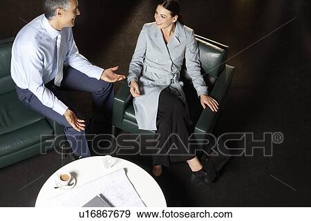 Businessman and businesswoman talking at office table elevated view View Large Photo Image Stock Photo - Businessman and businesswoman talking at office table elevated view. Fotosearch