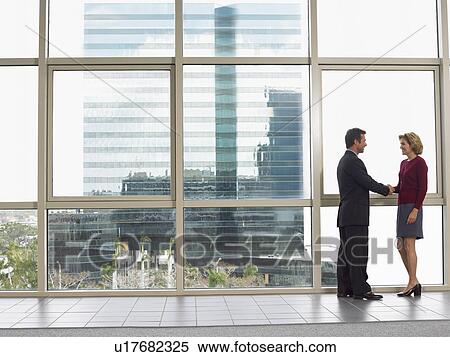 Businessman and woman shaking hands in office building View Large Photo Image Stock Photography - Businessman and woman shaking hands in office building. Fotosearch