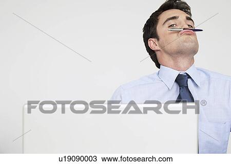 Businessman balancing pen on upper lip View Large Photo Image Stock Image - Businessman balancing pen on upper lip. Fotosearch