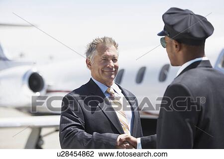 Businessman Beside private jet shaking hands with pilot View Large Photo Image Stock Image - Businessman Beside private jet shaking hands with pilot. Fotosearch